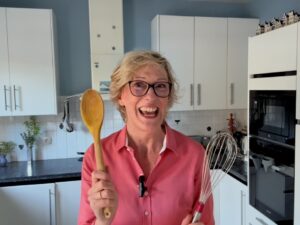 Jill Colonna holding a whisk and wooden spoon in her Paris kitchen